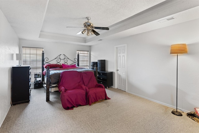 carpeted bedroom with ceiling fan, ornamental molding, a textured ceiling, and a tray ceiling