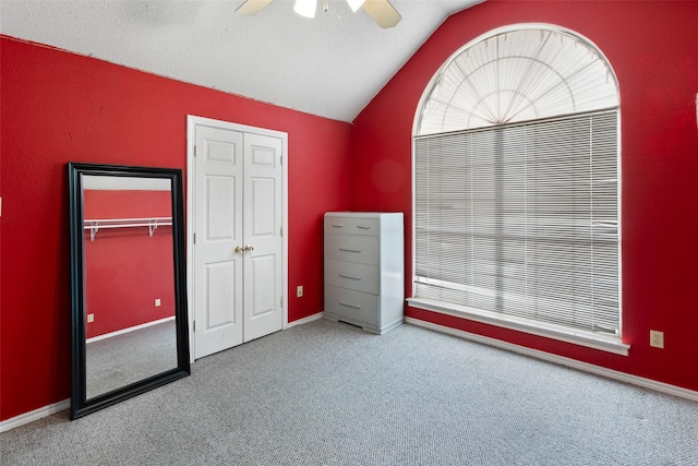 unfurnished bedroom featuring ceiling fan, lofted ceiling, a textured ceiling, and carpet