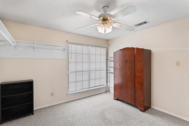 bedroom with ceiling fan, light carpet, and a textured ceiling