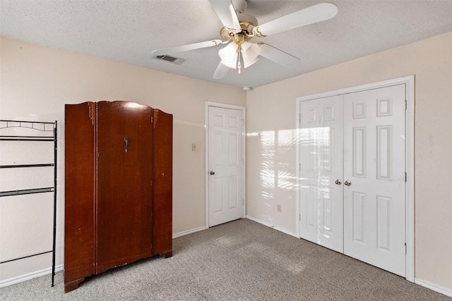 unfurnished bedroom with a textured ceiling, ceiling fan, and light colored carpet