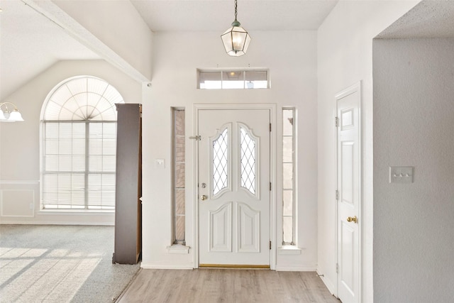 foyer entrance with a healthy amount of sunlight, light hardwood / wood-style floors, and vaulted ceiling