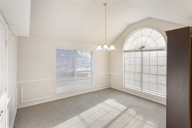 carpeted spare room with lofted ceiling and a notable chandelier