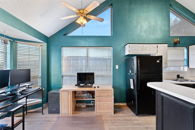 interior space with vaulted ceiling, ceiling fan, a textured ceiling, sink, and light hardwood / wood-style flooring