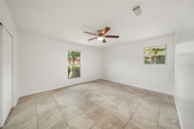 spare room with ceiling fan and light tile patterned flooring