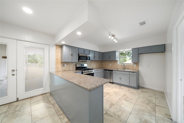 kitchen featuring gray cabinetry, stainless steel appliances, sink, kitchen peninsula, and decorative backsplash