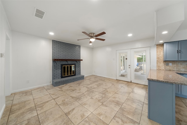 unfurnished living room featuring french doors, a brick fireplace, and ceiling fan