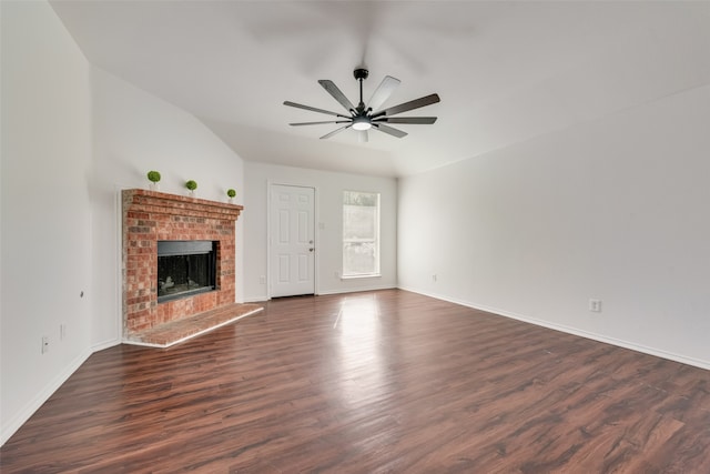 unfurnished living room featuring dark wood-type flooring, lofted ceiling, a brick fireplace, and ceiling fan