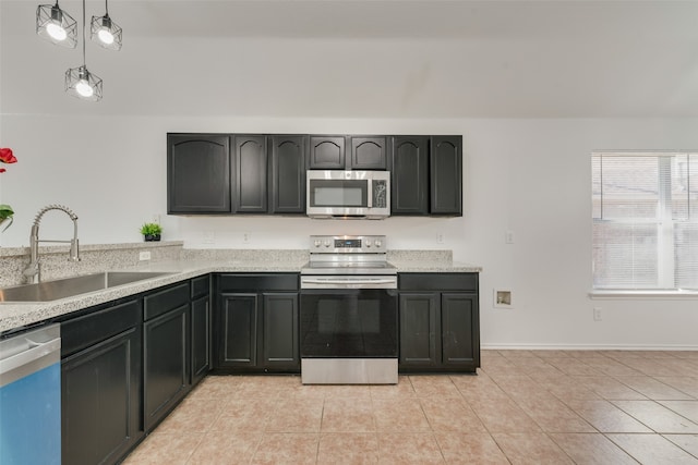 kitchen with appliances with stainless steel finishes, light stone counters, sink, and hanging light fixtures