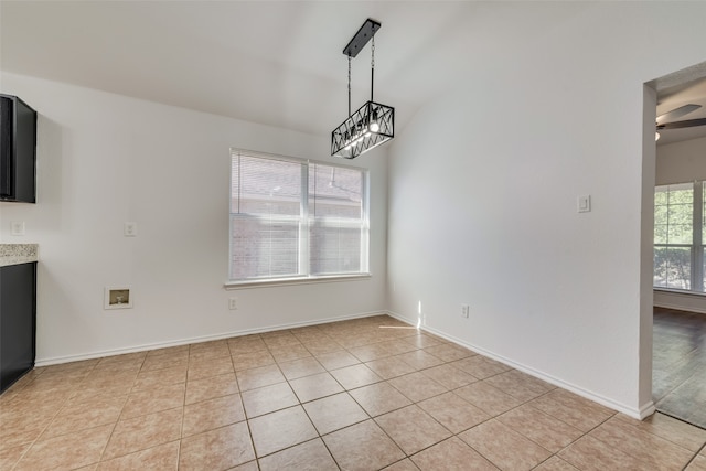 unfurnished dining area with ceiling fan with notable chandelier and light tile patterned floors