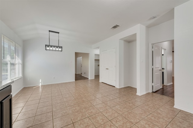 tiled spare room with vaulted ceiling