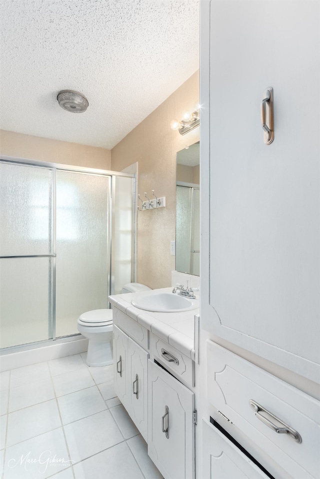 bathroom featuring vanity, toilet, a shower with shower door, and a textured ceiling