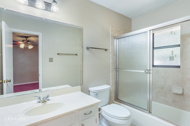 full bathroom with a textured ceiling, vanity, toilet, enclosed tub / shower combo, and ceiling fan