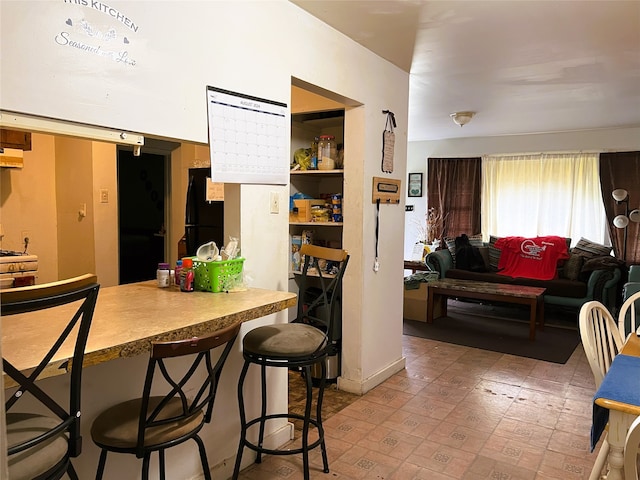 kitchen with a kitchen bar, freestanding refrigerator, and under cabinet range hood