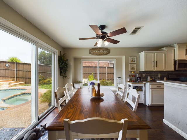 living room with dark wood-type flooring, a high ceiling, ceiling fan, and a fireplace