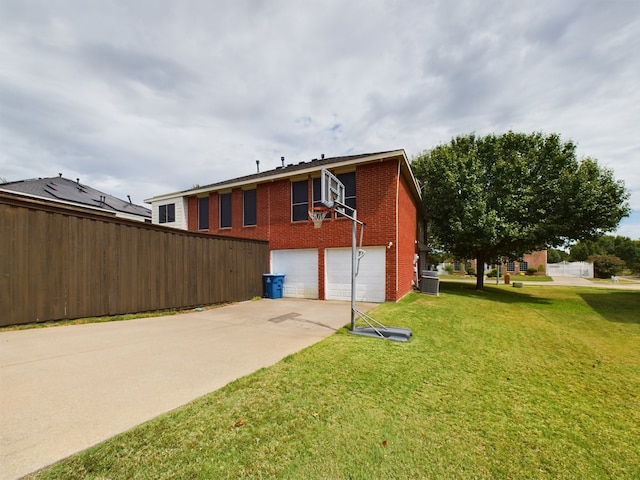 rear view of house with a garage, cooling unit, and a lawn