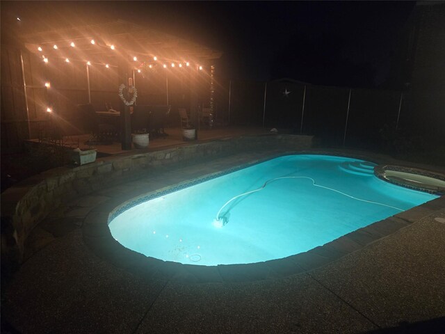 pool at twilight featuring an in ground hot tub