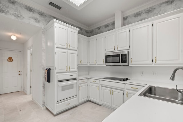 kitchen with stainless steel microwave, visible vents, oven, black electric stovetop, and a sink