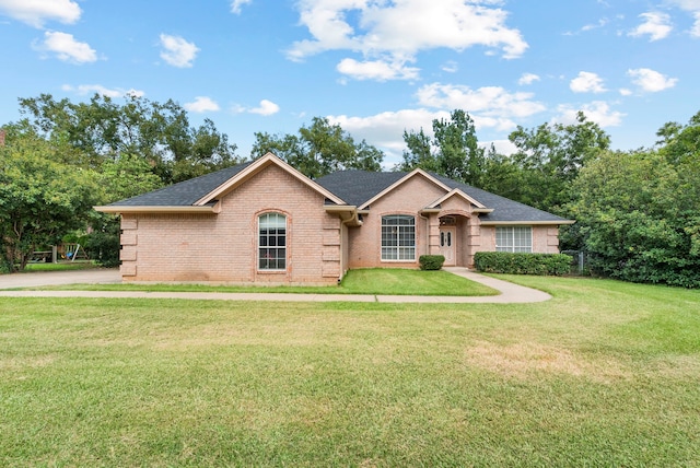 ranch-style home with brick siding, roof with shingles, and a front yard