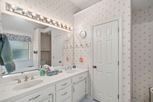 bathroom featuring a bath, toilet, ornamental molding, and vanity