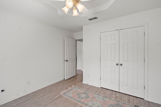 unfurnished bedroom featuring light wood-type flooring, ceiling fan, and a closet