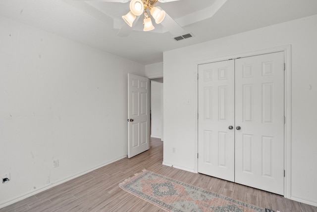 unfurnished bedroom featuring visible vents, baseboards, wood finished floors, a closet, and a ceiling fan