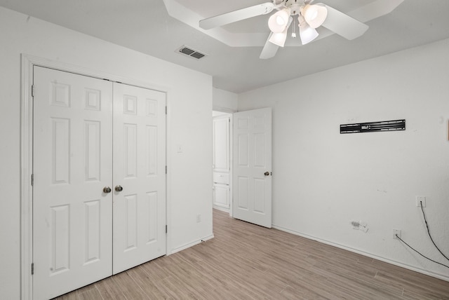 unfurnished bedroom with a ceiling fan, visible vents, baseboards, light wood-style floors, and a closet