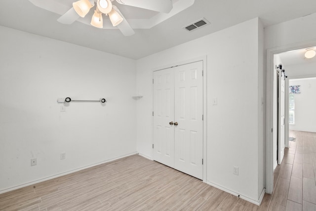 unfurnished bedroom with a closet, visible vents, light wood-type flooring, and ceiling fan