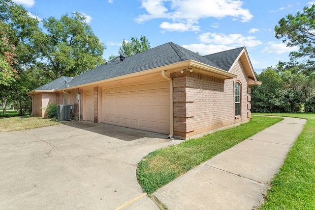 view of side of property with a lawn, a garage, and central AC unit