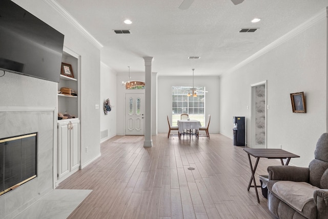 interior space featuring crown molding, a high end fireplace, ceiling fan with notable chandelier, light hardwood / wood-style floors, and a textured ceiling