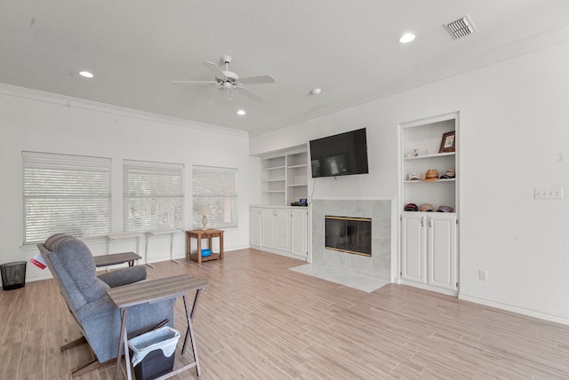 living room with ceiling fan, a tiled fireplace, and light hardwood / wood-style flooring