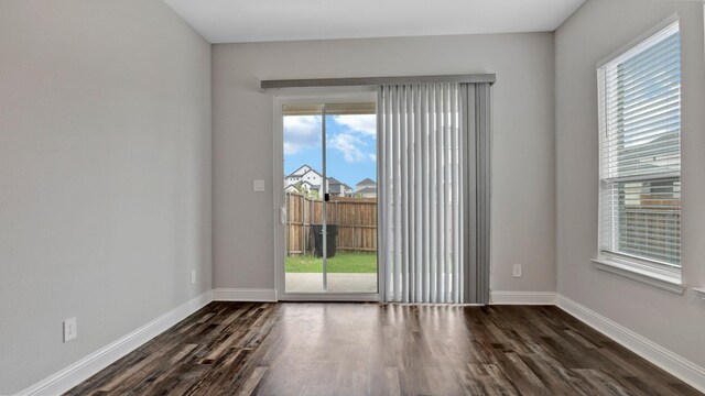 spare room with a wealth of natural light and dark wood-type flooring