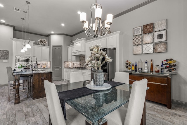 dining area with sink, light hardwood / wood-style floors, a notable chandelier, and ornamental molding