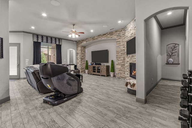 living room featuring ceiling fan, a fireplace, light hardwood / wood-style floors, and ornamental molding