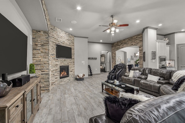 living room with a fireplace, light wood-type flooring, ceiling fan, and ornamental molding