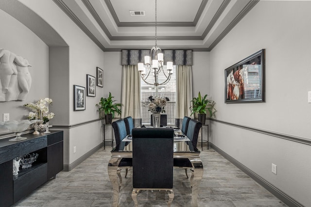 dining area featuring an inviting chandelier, a raised ceiling, plenty of natural light, and ornamental molding