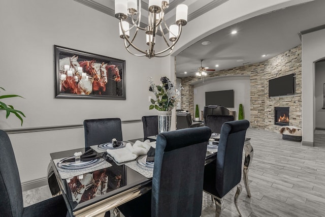 dining area with a fireplace, ceiling fan with notable chandelier, light hardwood / wood-style flooring, and crown molding