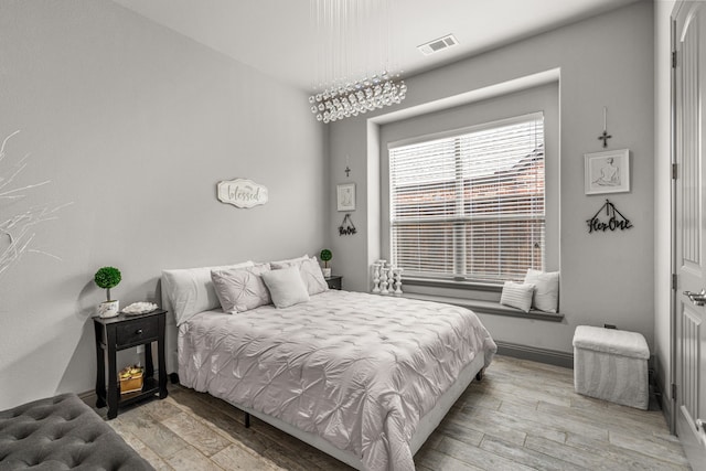 bedroom with light wood-type flooring and an inviting chandelier