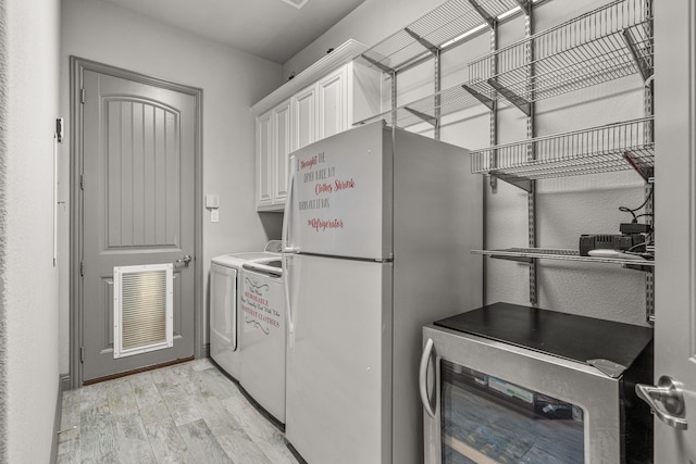 washroom with separate washer and dryer, beverage cooler, cabinets, and light wood-type flooring