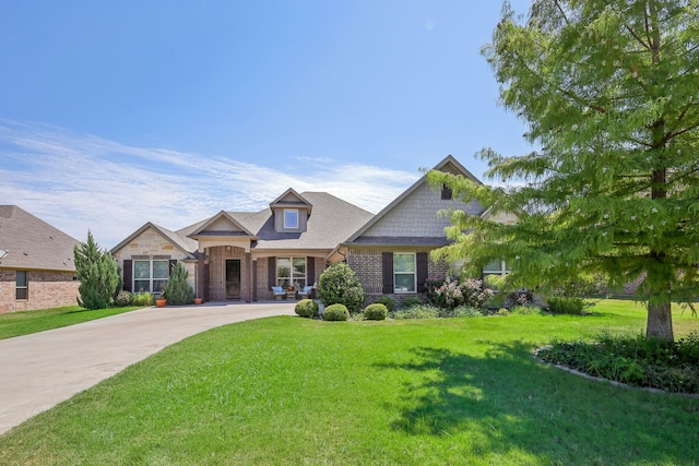 craftsman house featuring brick siding, driveway, and a front lawn