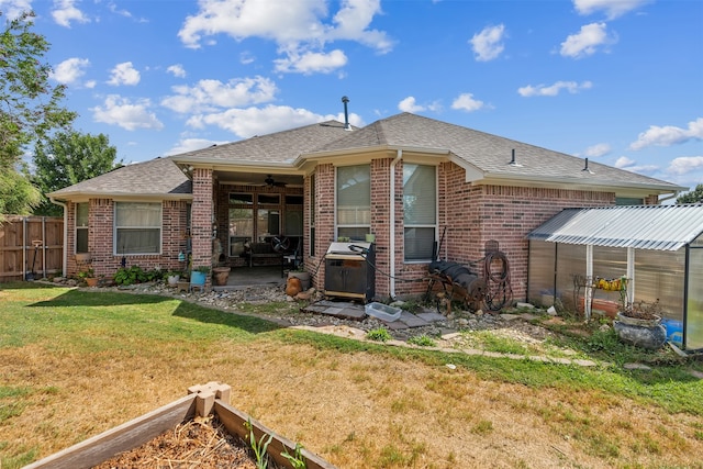 rear view of property featuring ceiling fan, a lawn, and a patio area