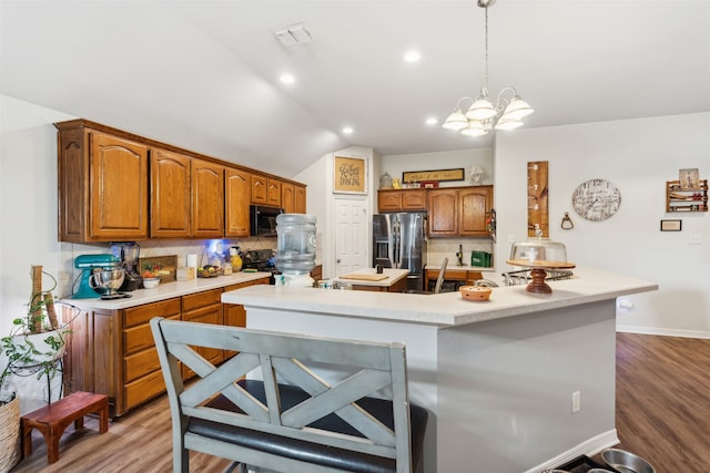 kitchen with an island with sink, lofted ceiling, black appliances, and decorative backsplash