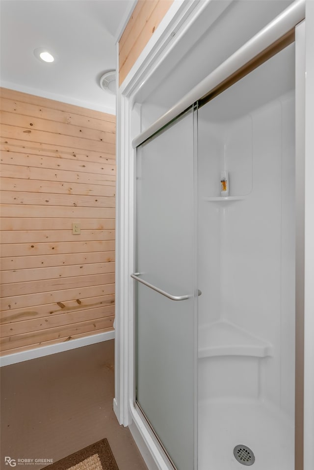 bathroom with a shower with door and wooden walls