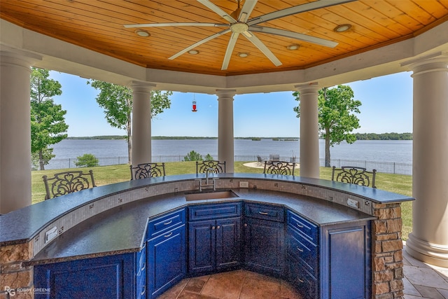 view of patio / terrace featuring an outdoor kitchen, a water view, ceiling fan, and a wet bar