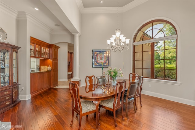 dining area with a chandelier, ornamental molding, dark wood-type flooring, and decorative columns