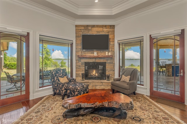 living room featuring a stone fireplace, hardwood / wood-style floors, and ornamental molding