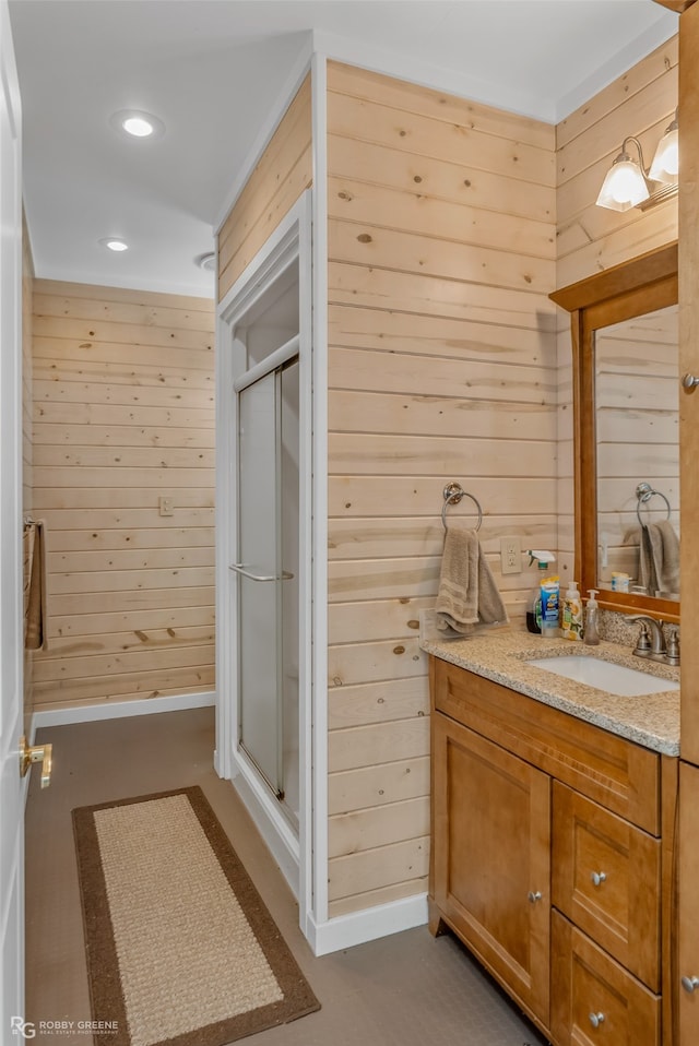 bathroom with vanity, wood walls, and walk in shower