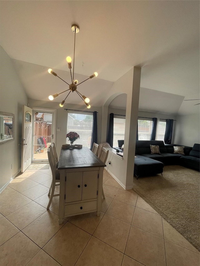 tiled dining room featuring lofted ceiling, plenty of natural light, and a notable chandelier