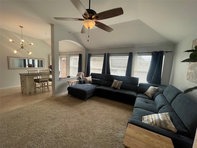 carpeted living room with ceiling fan with notable chandelier and high vaulted ceiling