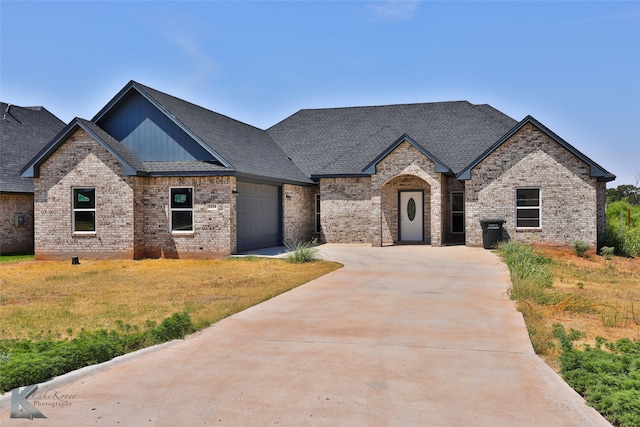 french country style house featuring a garage and a front yard