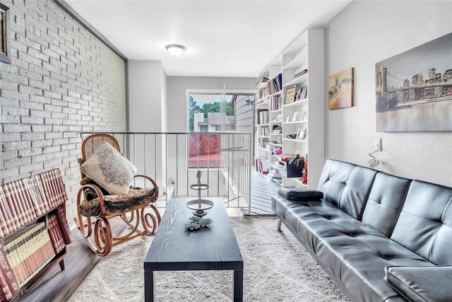 living room with brick wall and hardwood / wood-style flooring